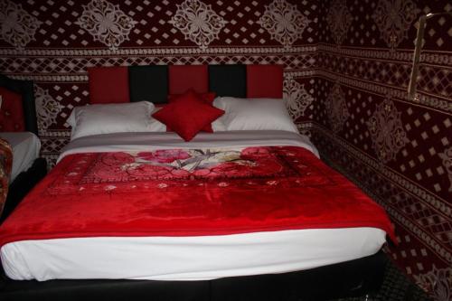 a large bed with a red blanket on it at Wadi Rum Quiet Village Camp in Wadi Rum