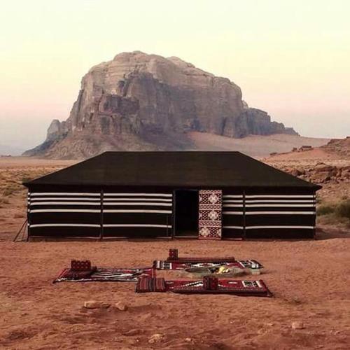 a building in the desert with a mountain in the background at Wadi Rum Quiet Village Camp in Wadi Rum