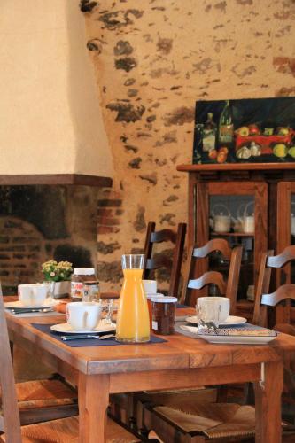 - une table en bois avec des assiettes et une carafe dans l'établissement Les chambres d'hôtes de La Métairie du Bourg, aux Herbiers