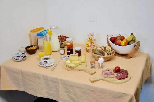 un tavolo con un mucchio di cibo e un cesto di frutta di Le Cerneux-au-Maire a Les Bois