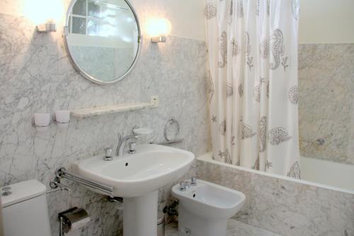 a white bathroom with a sink and a mirror at Barony Le Pergole holiday apartments Lugano in Lugano