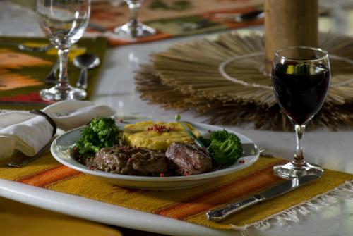 a plate of food with meat and broccoli next to a glass of wine at Vilangelim Eco-Pousada in Imbassai