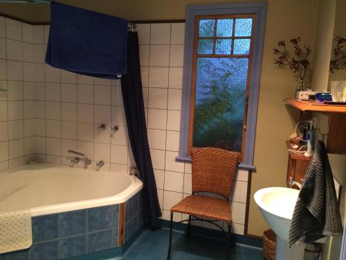 a bathroom with a tub and a chair and a window at Tramway Cottage in Strahan