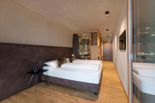 a bedroom with a large white bed and a bathroom at Ellgass Allgäu Hotel in Eglofs