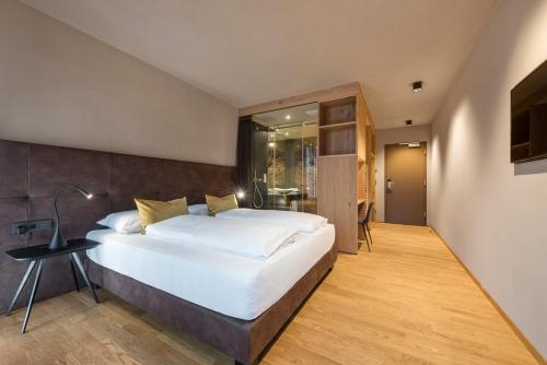 a bedroom with a large white bed and a desk at Ellgass Allgäu Hotel in Eglofs