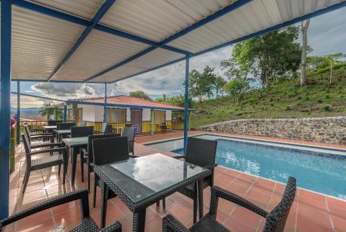 a patio with tables and chairs next to a swimming pool at Finca Hotel Guayacundo in Vergara