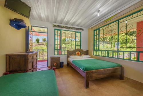 a bedroom with a bed and some windows at Finca Hotel Guayacundo in Vergara