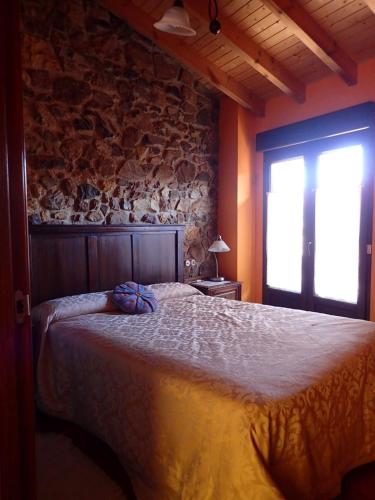 a bedroom with a bed and a stone wall at El Requexu de Cervera in Cervera