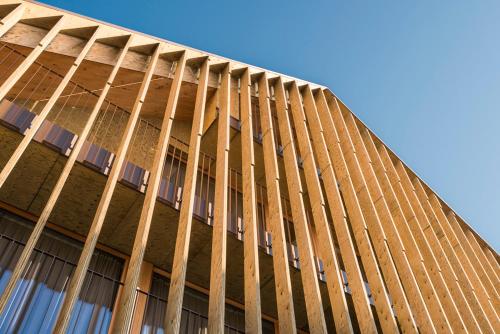 a tall building with wooden poles on the side of it at Ellgass Allgäu Hotel in Eglofs