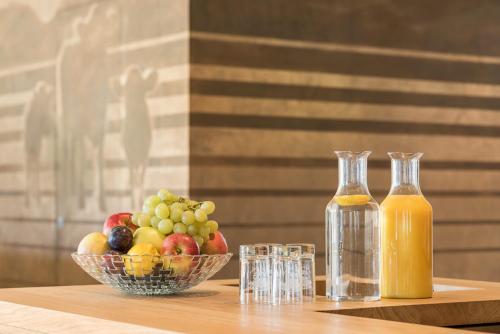 a bowl of fruit and two bottles of juice on a table at Ellgass Allgäu Hotel in Eglofs