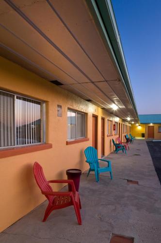 a row of colorful chairs sitting on the side of a building at Sunset Motel Moriarty in Moriarty