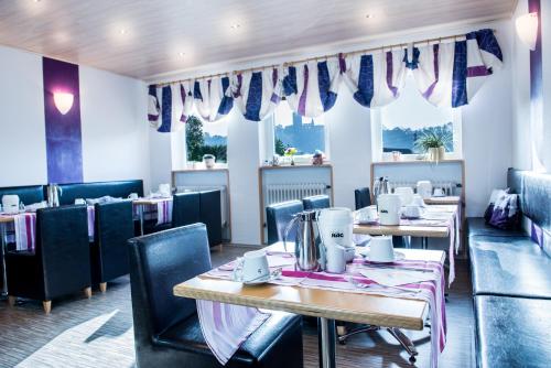 jadalnia ze stołami, krzesłami i oknami w obiekcie Hotel Burgblick w mieście Thallichtenberg