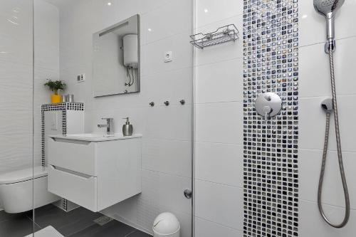 a white bathroom with a shower and a sink at Villa Sukara in Makarska