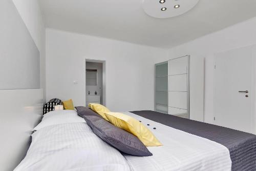 a white bedroom with a large bed with pillows at Villa Sukara in Makarska