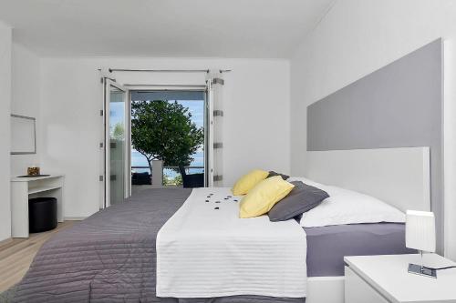a white bedroom with a large bed with yellow pillows at Villa Sukara in Makarska