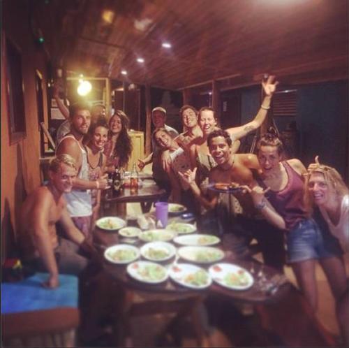 a group of people sitting around a table at Coral Reef Surf Hostel and Camp in Tamarindo