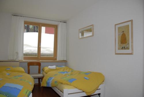 a bedroom with two beds and a window at Ferienwohnung Alte Bäckerei in Mürren