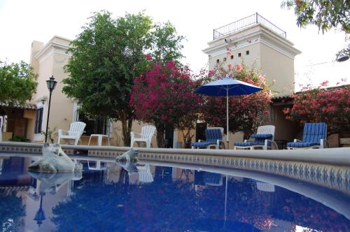 a pool with chairs and an umbrella next to a building at Hotel Quinta Minera in Cosalá