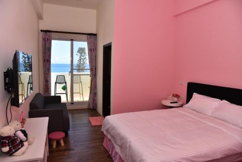 a bedroom with pink walls and a bed and a balcony at Spring Enjoy Color B&B in Taitung City