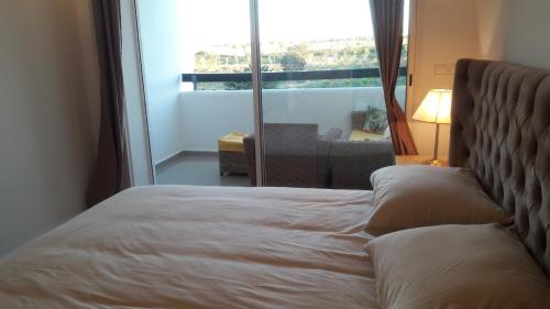 a bed in a room with a large window at Appart Asilah Marina Golf in Asilah