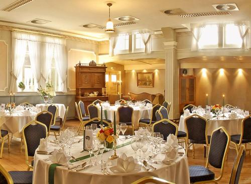 a room filled with tables and chairs with white table cloth at Landgasthaus & Hotel Lindenhof in Königslutter am Elm