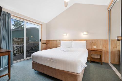 a bedroom with a large bed and a large window at Kendalls Beach Holiday Park in Kiama