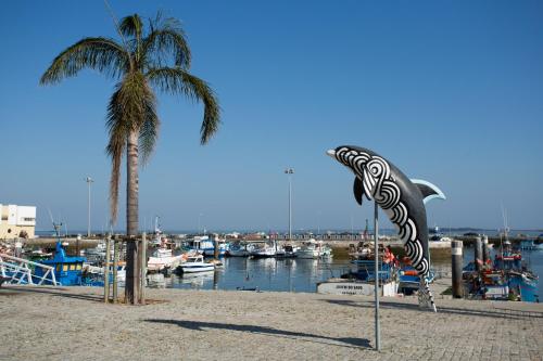 a palm tree and a flag on a beach with boats at Hotel Solaris in Setúbal