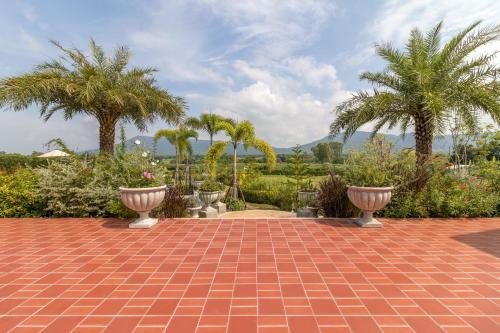 a brick walkway with palm trees in the background at Chateau de Prim Khao Yai in Ban Sap Phlu