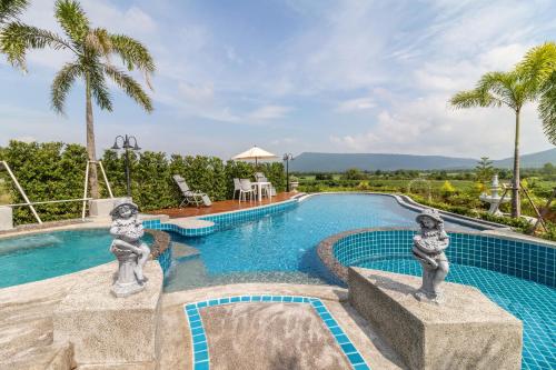a swimming pool with two statues in a resort at Chateau de Prim Khao Yai in Ban Sap Phlu