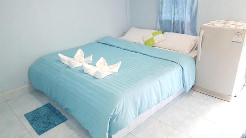 Una cama azul con dos almohadas blancas. en Montra Guesthouse en Ranong