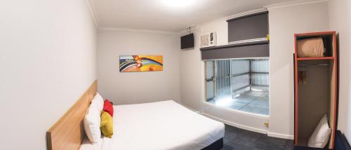 a small bedroom with a bed and a window at Links Hotel in Adelaide
