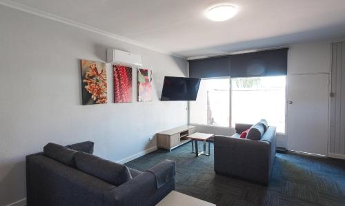 a living room with two couches and a table at Links Hotel in Adelaide