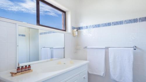 a white bathroom with a sink and a mirror at Driftwood Beachfront @ Vincentia in Vincentia