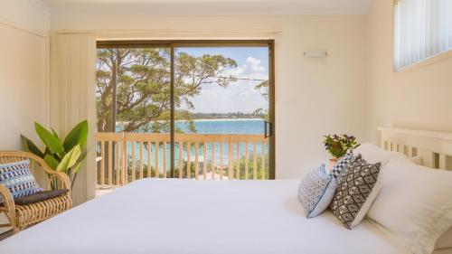 a bedroom with a bed and a view of the ocean at Driftwood Beachfront @ Vincentia in Vincentia