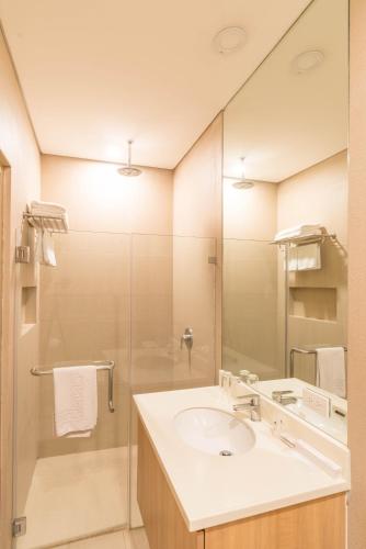 a bathroom with a sink and a shower with a mirror at Madison 101 Hotel + Tower in Manila