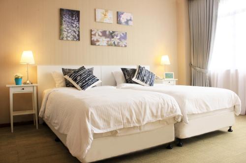 una camera con 2 letti con coperte e cuscini bianchi di Alocassia Serviced Apartments a Singapore