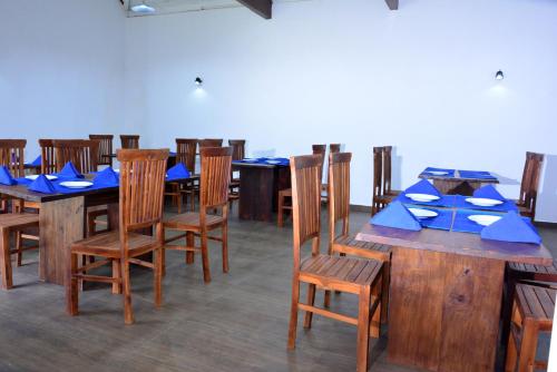 a dining room with wooden tables and chairs with blue napkins at Paradise Forest Garden in Matale