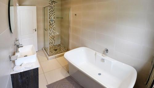 a white bathroom with a tub and a shower at Vine Guesthouse in Stellenbosch