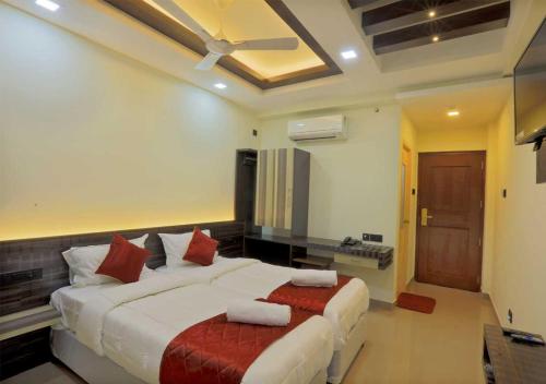 a bedroom with a large white bed with red pillows at Kenz Residency in Cochin