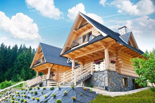 a log home with a blue roof at Domki pod lasem in Nowe Bystre