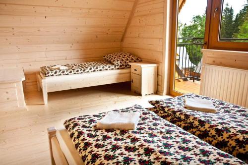 a room with two beds in a log cabin at Domki pod lasem in Nowe Bystre