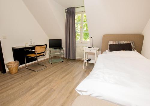 um quarto com uma cama e uma secretária com um computador em Hotel Gut Grossrotter Hof (ehem. Hotel Schmitte) em Colônia