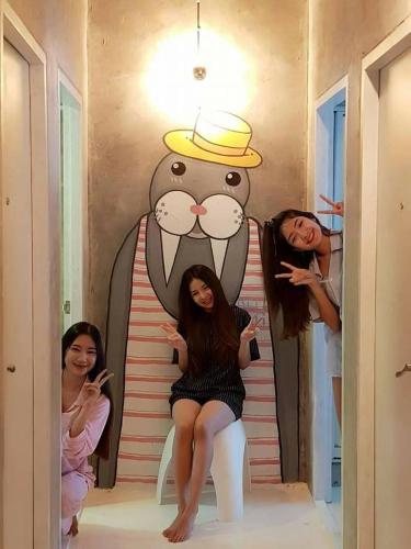 a group of women sitting on the stairs in front of a cartoon character at Pastelhouse hostel in Bangkok
