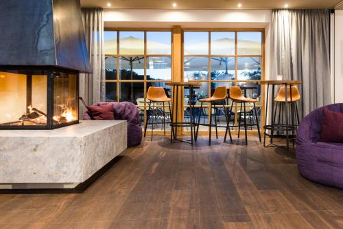 a living room with a fireplace and tables and chairs at Hotel Hörterer Der Hammerwirt in Siegsdorf