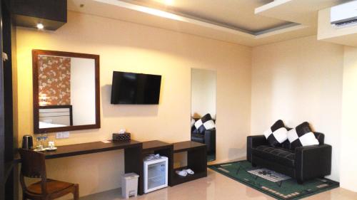 a living room with a black couch and a mirror at Grand Madani Hotel in Mataram