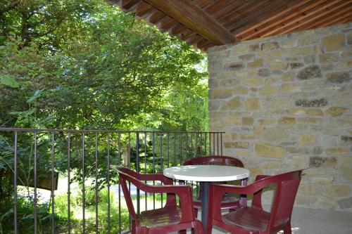 a table and chairs on a porch with a stone wall at Auberge Les Sibourgs in Bourdeaux