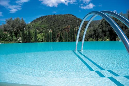 a pool of blue water with a mountain in the background at Château Saint-Martin & Spa, Oetker Hotels in Vence