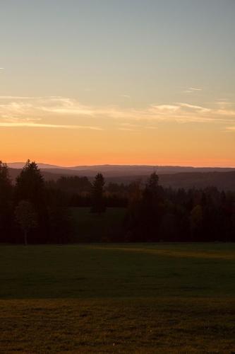 a sunset over a field with trees in the distance at Le Cerneux-au-Maire in Les Bois