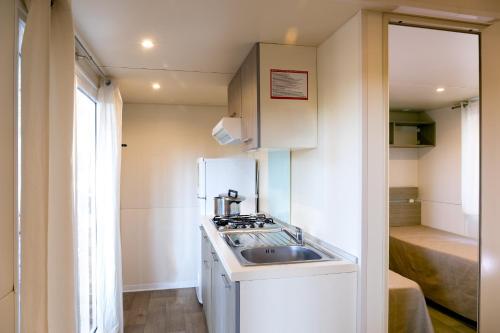 a small kitchen with a sink and a refrigerator at Giannella Camping in Orbetello