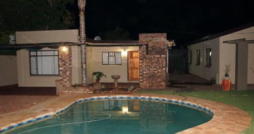 a swimming pool in front of a house at night at Mckala Guesthouse in Kimberley